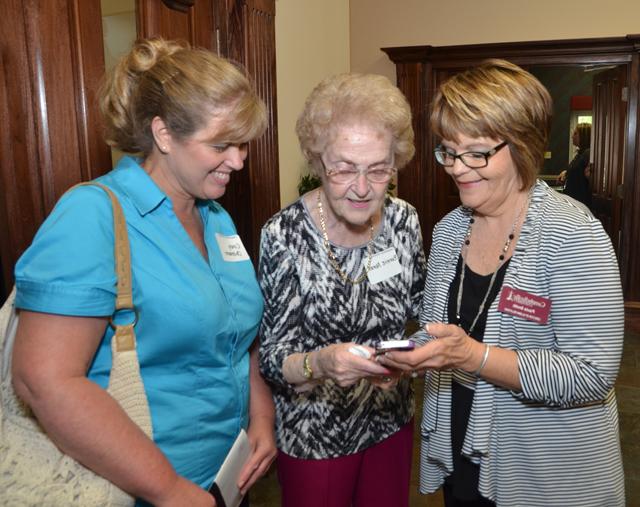 Paula Smith, director of alumni relations, shows pictures  to Bonnie Abner of Louisville, center, and Cindy  Ohlmann, whose daughter, Taylor, is a CU student.  (Campbellsville University Photo by Joan C. McKinney)